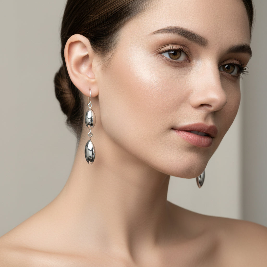 A pair of silver drop earrings with two elongated oval beads on each earring, 