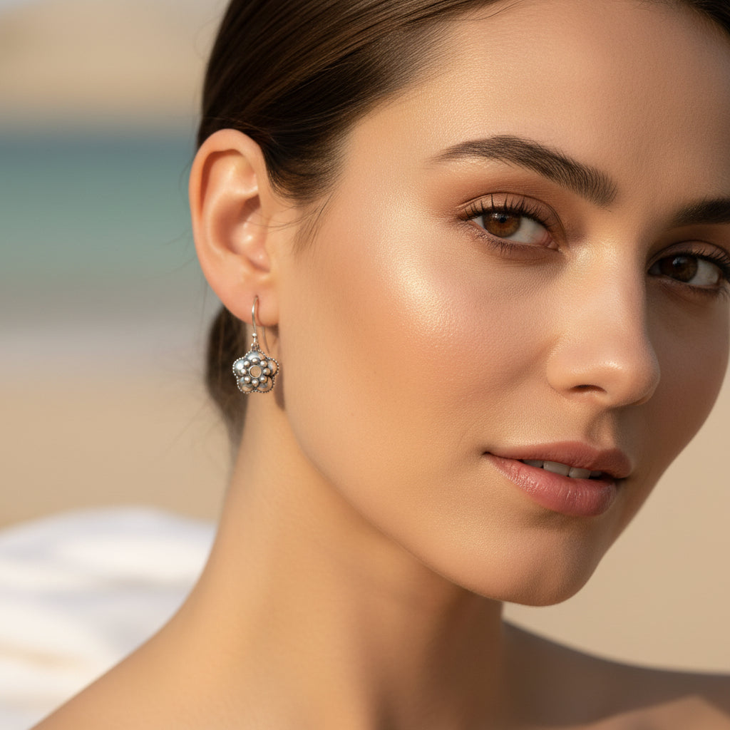 A silver-toned dangle earring with a textured floral pendant, 