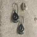 These small silver hook style earrings in the shape of a tear with sweet details are a delightful accessory that combines elegance, sentimentality, and a touch of whimsy.